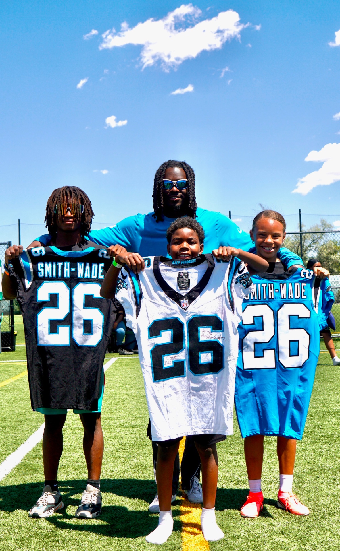 Chau Smith-Wade posing with young campers holding signed jerseys